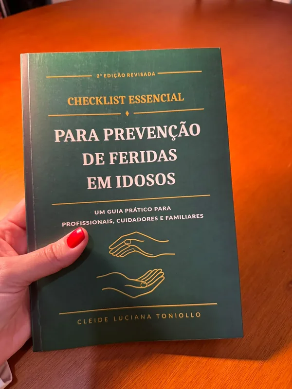 Livro Checklist Essencial para Prevenção de Feridas em Idosos segurado na mão